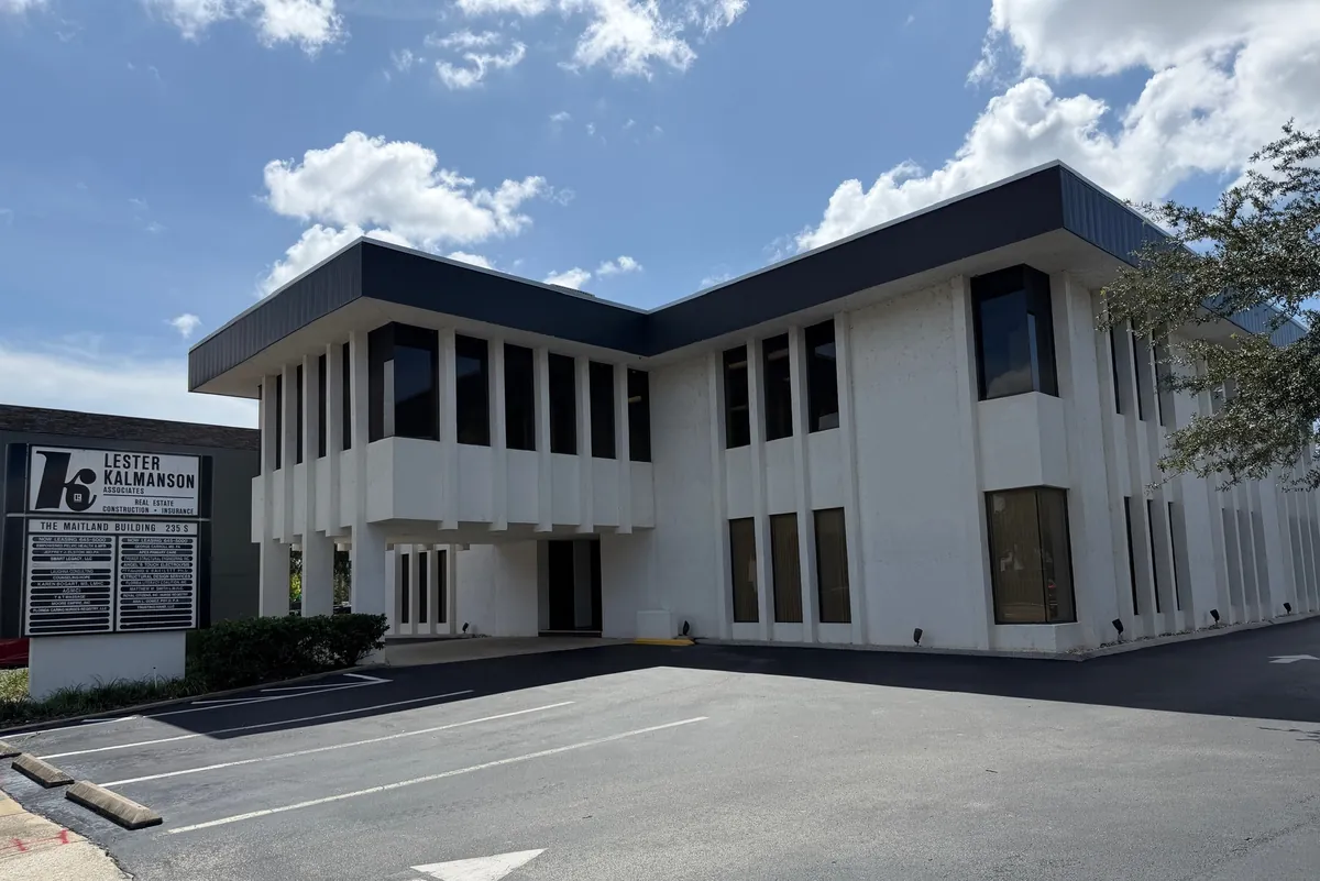 The two-story white office building at 235 Maitland Avenue South, seen across its parking lot