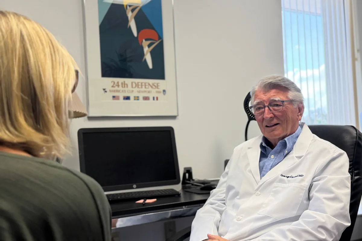 Dr. Carroll talking with a woman seated across his desk, her back to the camera