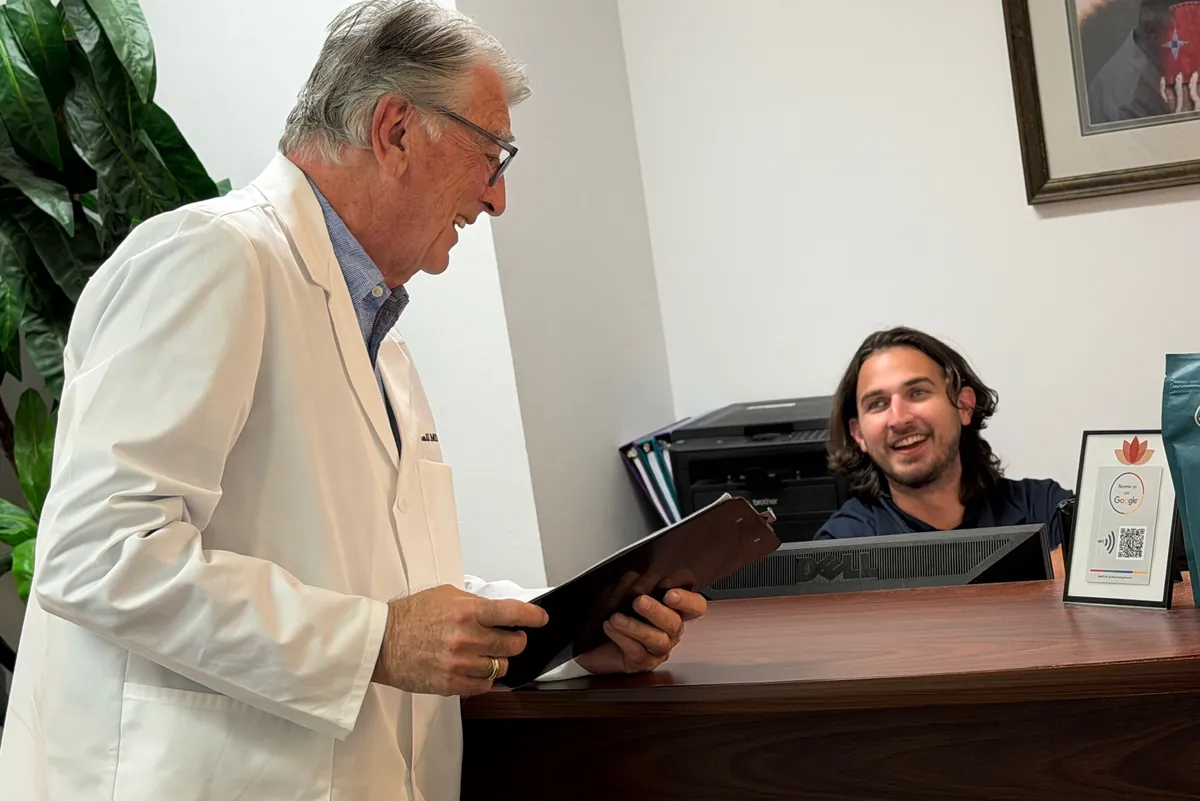 Dr. Carroll holding a clipboard at the front desk, laughing with the receptionist