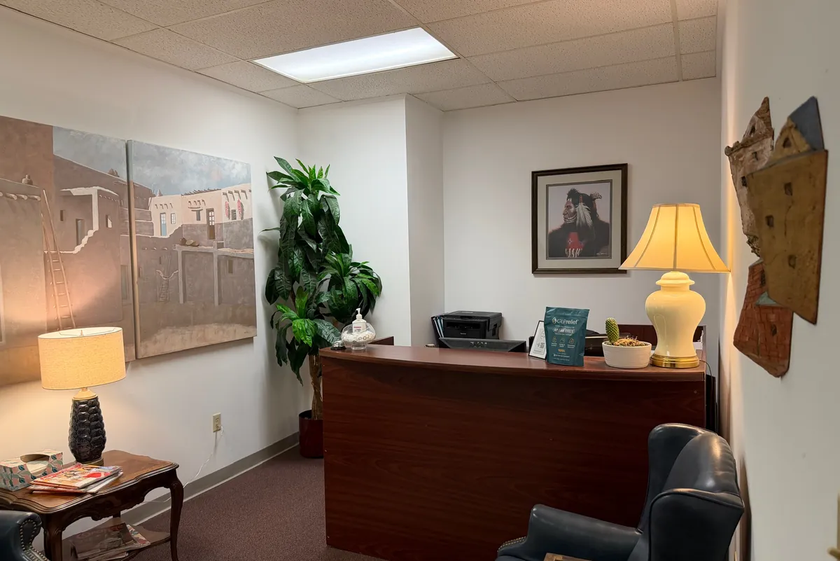 The waiting room: leather wingback chairs, a patterned rug, and the reception desk under a table lamp